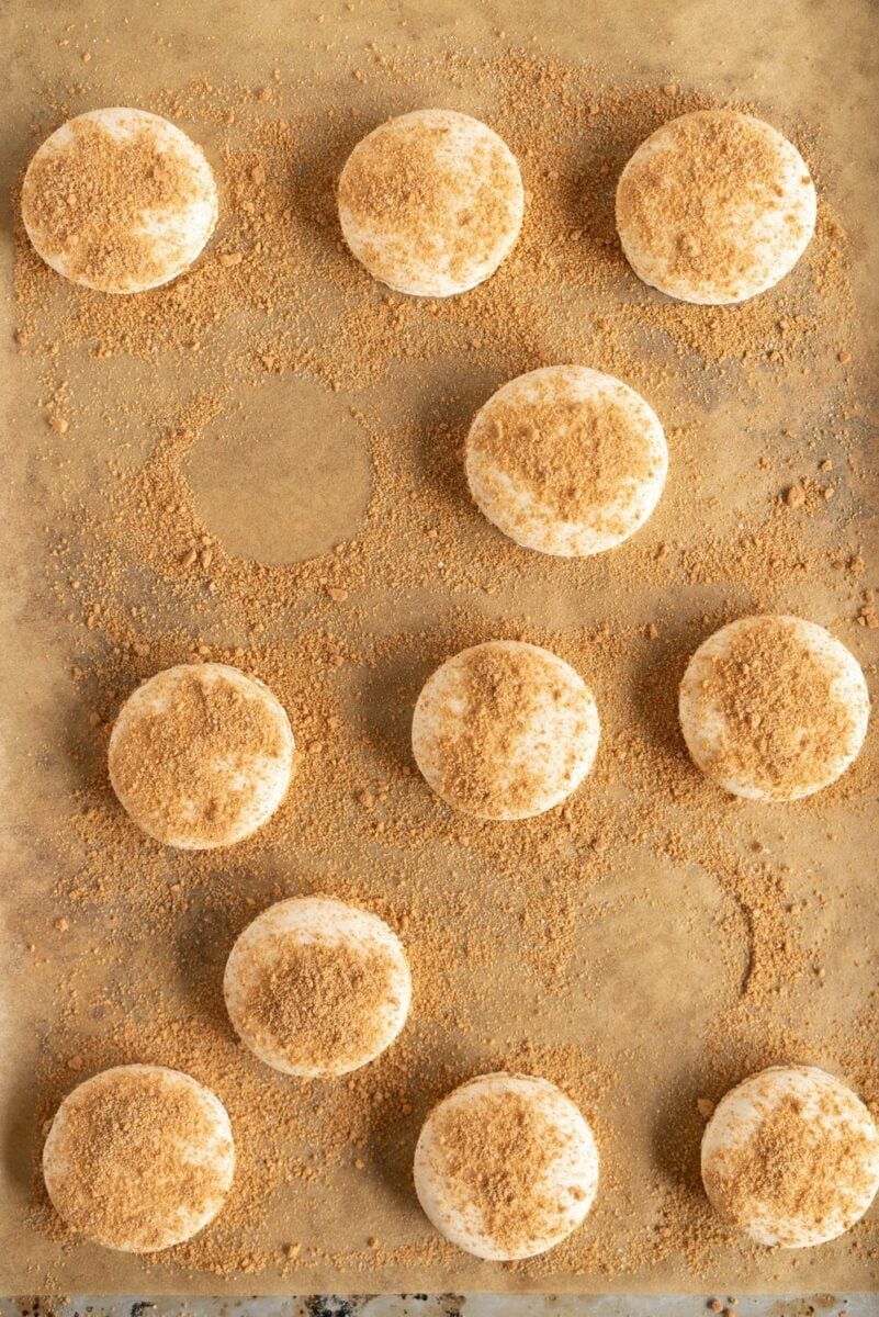 macaron shells on a brown background with graham cracker crumbs
