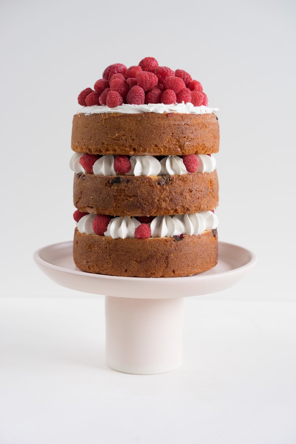 Raspberry and Almond cake - a perfectly dense almond meal cake, lightly scented with lemon, and with a layer of fresh raspberries baked into each layer. Layered with vanilla swiss meringue buttercream and more fresh raspberries. perfect for Mother's day or any other special occasion.