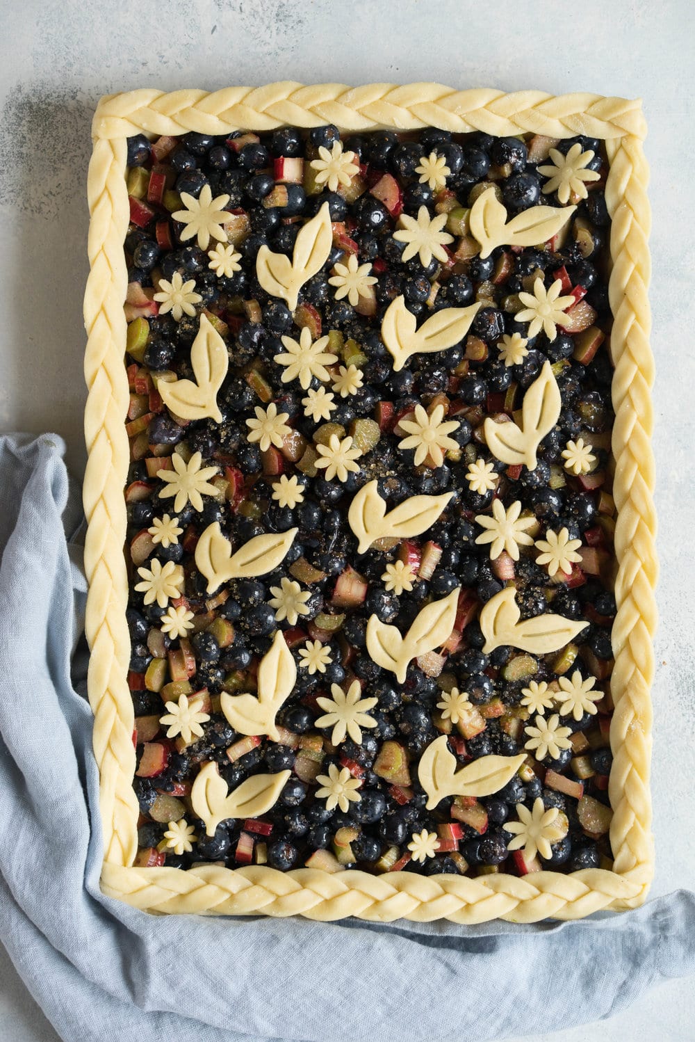 Blueberry and Rhubarb Slab pie - the ideal summer dessert for feeding a crowd! Flaky homemade pie crust is filled with a blueberry rhubarb filling before being topped with fun pie dough decorations then baked to perfection. #blueberry #rhubarb #slabpie #familypie #blueberryrhubarb