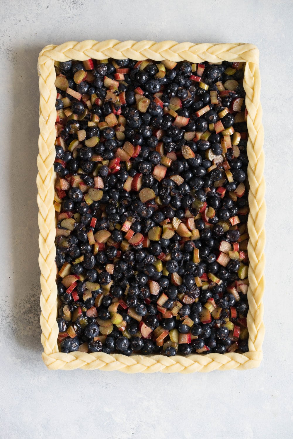 Blueberry and Rhubarb Slab pie - the ideal summer dessert for feeding a crowd! Flaky homemade pie crust is filled with a blueberry rhubarb filling before being topped with fun pie dough decorations then baked to perfection. #blueberry #rhubarb #slabpie #familypie #blueberryrhubarb