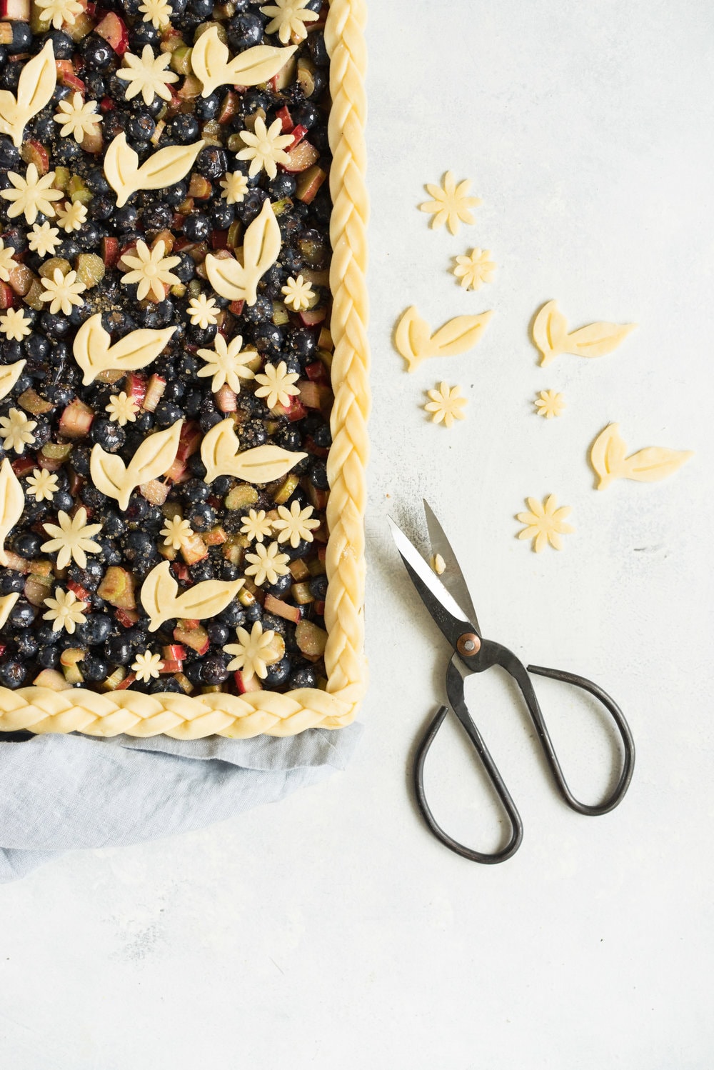 Blueberry and Rhubarb Slab pie - the ideal summer dessert for feeding a crowd! Flaky homemade pie crust is filled with a blueberry rhubarb filling before being topped with fun pie dough decorations then baked to perfection. #blueberry #rhubarb #slabpie #familypie #blueberryrhubarb