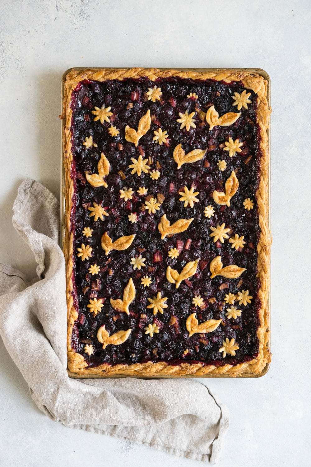 Blueberry and Rhubarb Slab pie - the ideal summer dessert for feeding a crowd! Flaky homemade pie crust is filled with a blueberry rhubarb filling before being topped with fun pie dough decorations then baked to perfection. #blueberry #rhubarb #slabpie #familypie #blueberryrhubarb