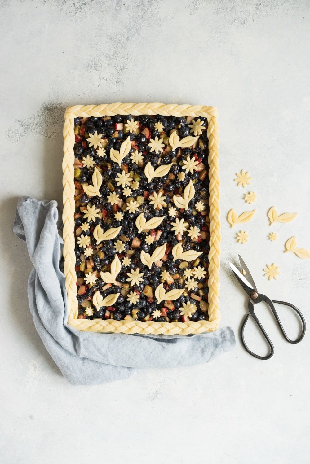 Blueberry and Rhubarb Slab pie - the ideal summer dessert for feeding a crowd! Flaky homemade pie crust is filled with a blueberry rhubarb filling before being topped with fun pie dough decorations then baked to perfection. #blueberry #rhubarb #slabpie #familypie #blueberryrhubarb
