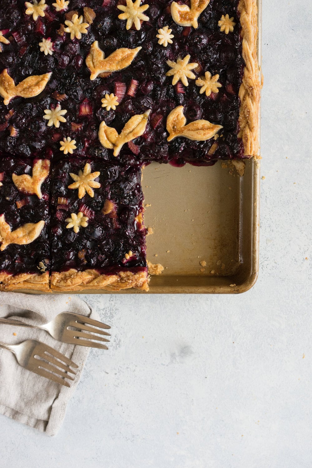Blueberry and Rhubarb Slab pie - the ideal summer dessert for feeding a crowd! Flaky homemade pie crust is filled with a blueberry rhubarb filling before being topped with fun pie dough decorations then baked to perfection. #blueberry #rhubarb #slabpie #familypie #blueberryrhubarb