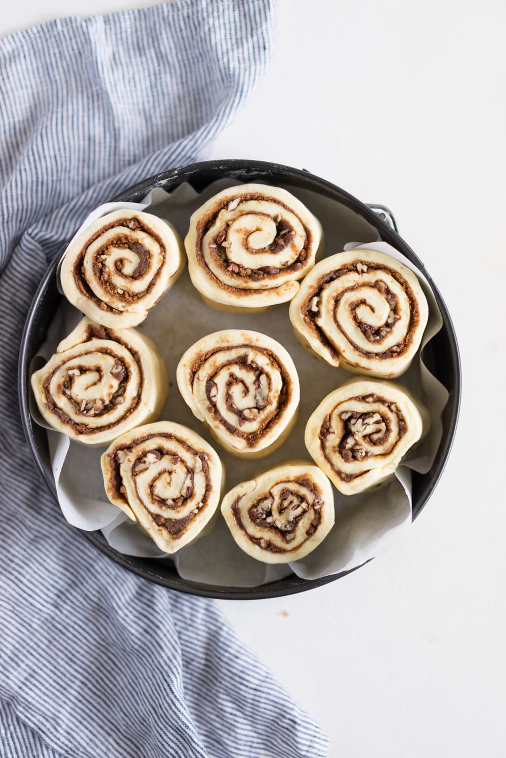 Overnight Cinnamon Buns with Cream Cheese Frosting - Pillowy brioche that is prepared the night before, then rolled out the next morning, stuffed with cinnamon sugar and toasted peanuts, then smothered in cream cheese frosting while still warm. The perfect treat to please a crowd. #cinnamonrolls #overnight #brioche