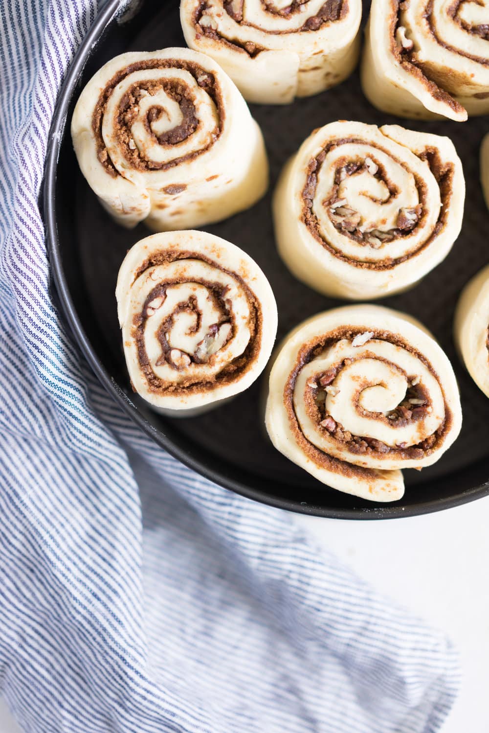 Overnight Cinnamon Buns with Cream Cheese Frosting - Pillowy brioche that is prepared the night before, then rolled out the next morning, stuffed with cinnamon sugar and toasted peanuts, then smothered in cream cheese frosting while still warm. The perfect treat to please a crowd. #cinnamonrolls #overnight #brioche