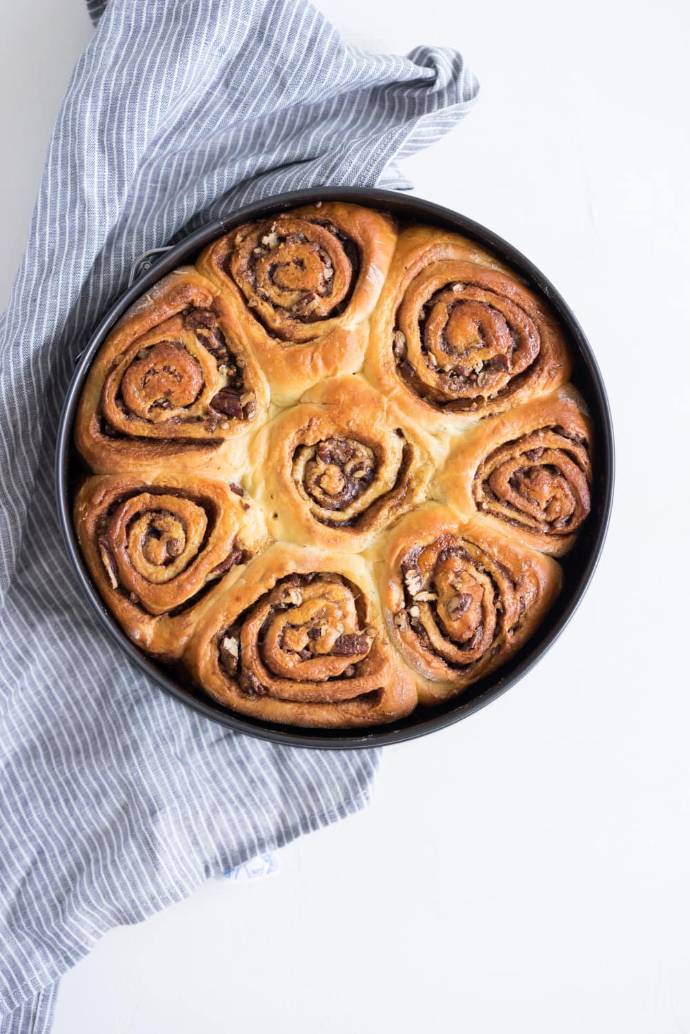 Overnight Cinnamon Buns with Cream Cheese Frosting - Pillowy brioche that is prepared the night before, then rolled out the next morning, stuffed with cinnamon sugar and toasted peanuts, then smothered in cream cheese frosting while still warm. The perfect treat to please a crowd. #cinnamonrolls #overnight #brioche
