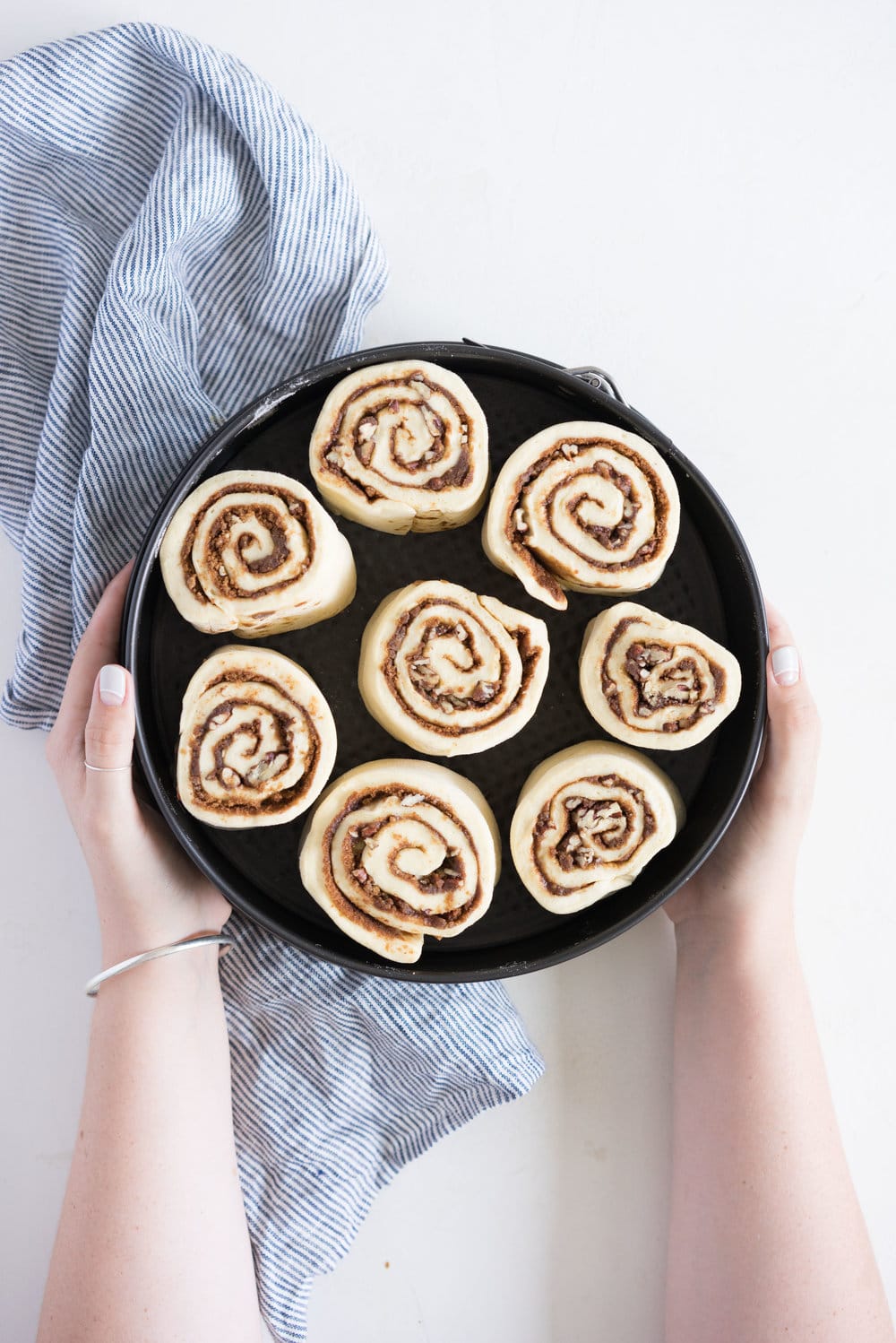 Overnight Cinnamon Buns with Cream Cheese Frosting - Pillowy brioche that is prepared the night before, then rolled out the next morning, stuffed with cinnamon sugar and toasted peanuts, then smothered in cream cheese frosting while still warm. The perfect treat to please a crowd. #cinnamonrolls #overnight #brioche