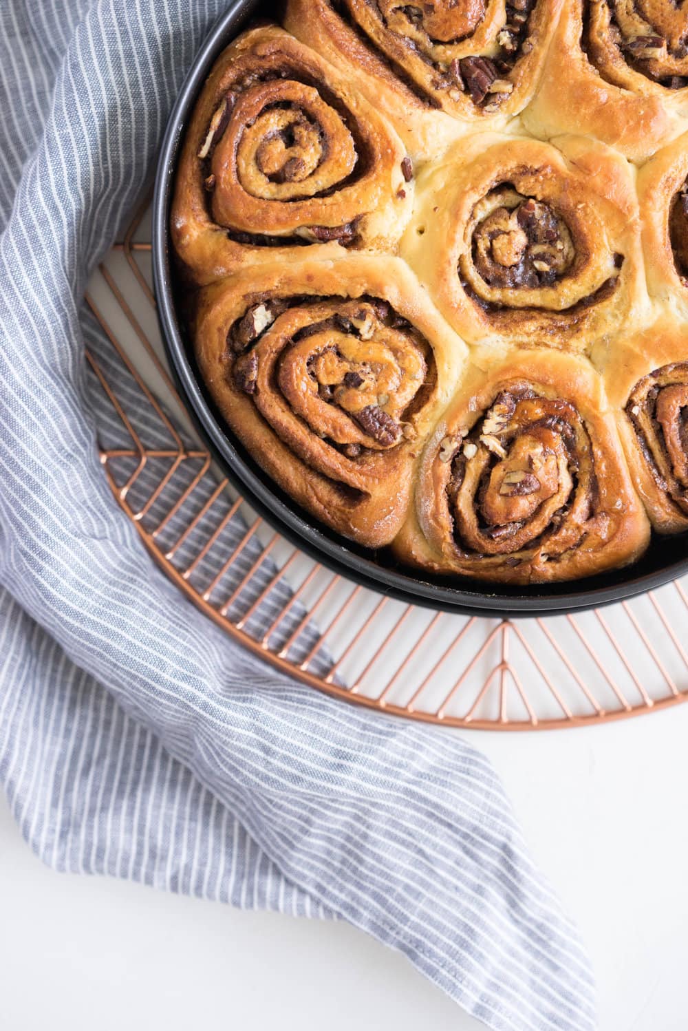 Overnight Cinnamon Buns with Cream Cheese Frosting - Pillowy brioche that is prepared the night before, then rolled out the next morning, stuffed with cinnamon sugar and toasted peanuts, then smothered in cream cheese frosting while still warm. The perfect treat to please a crowd. #cinnamonrolls #overnight #brioche