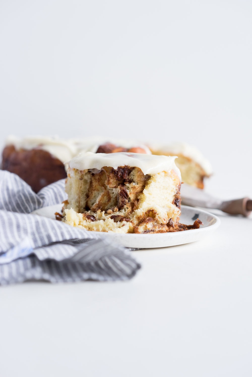 Overnight Cinnamon Buns with Cream Cheese Frosting - Pillowy brioche that is prepared the night before, then rolled out the next morning, stuffed with cinnamon sugar and toasted peanuts, then smothered in cream cheese frosting while still warm. The perfect treat to please a crowd. #cinnamonrolls #overnight #brioche