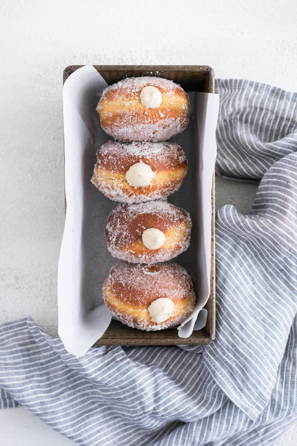 Gingerbread doughnuts with a spiced brown sugar diplomat cream. Pillowy brioche dough, spiced lightly with ginger and molasses, are stuffed with a light and creamy filling which is loaded with christmas spice. A perfect little package of holiday cheer