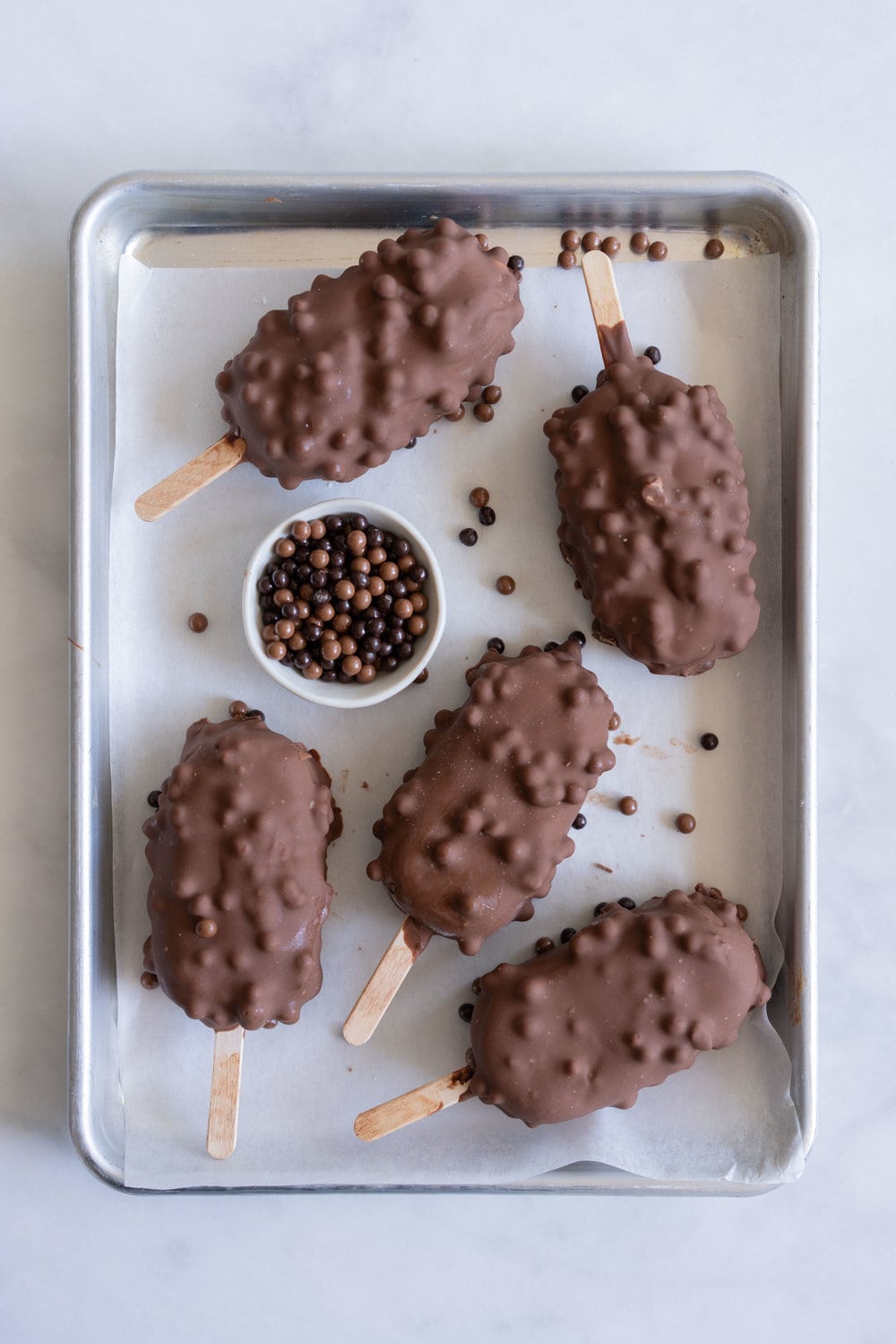 Rocky Road Ice Cream Pops by Cloudy Kitchen. Rich Chocolate ice cream is studded with marshmallow and turkish delight pieces, frozen into a pop, then dipped in creamy milk chocolate with crispy pearls. #Rockyroad #icecreampop #popsicle #cloudykitchen