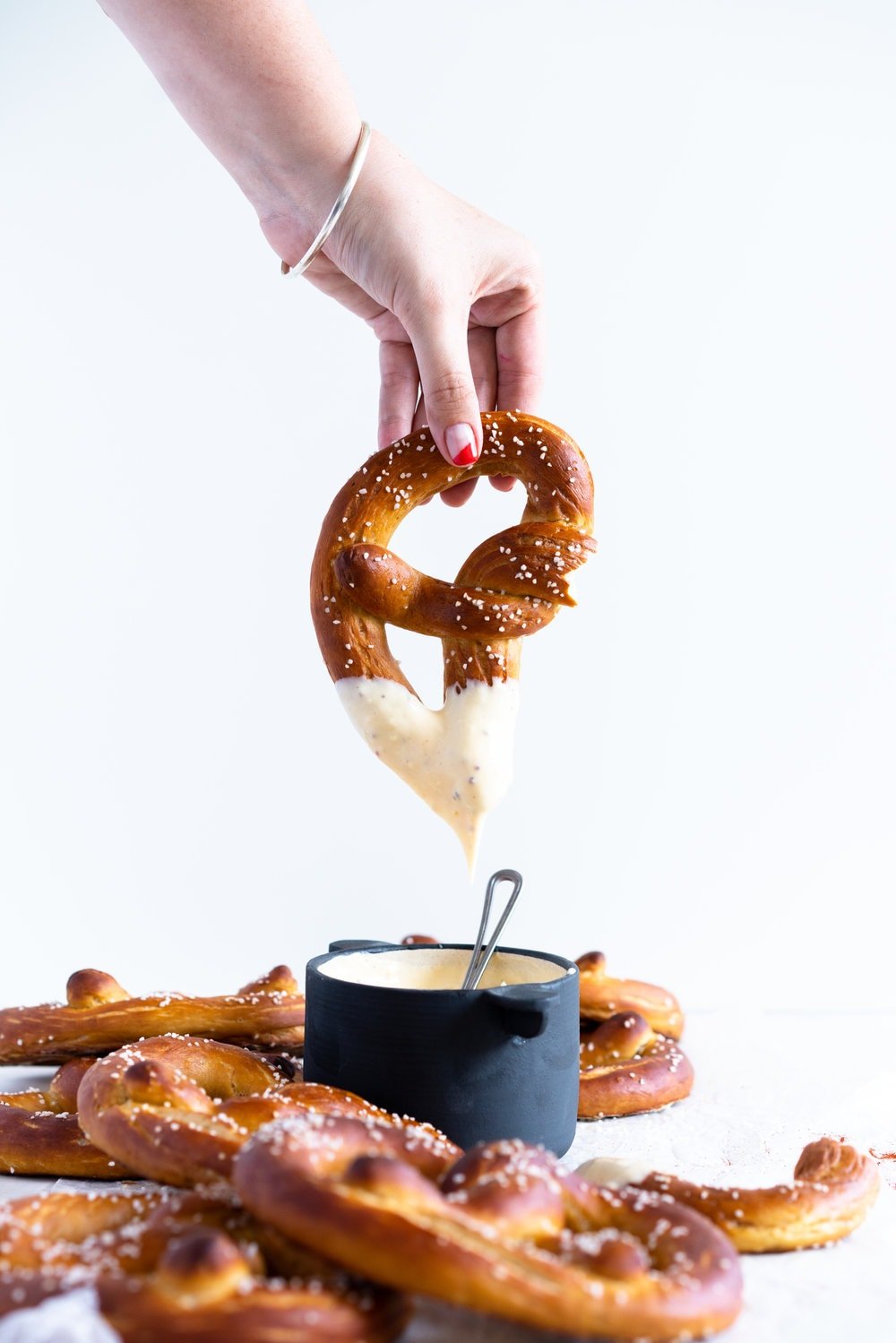 Authentic pretzels, baked until perfectly soft and golden brown, dipped in a super easy cheesy mustard dipping sauce that comes together extremely quickly. The perfect snack for a crowd. #pretzels #cheesesauce #cheesedip #americancheese #bread #homemadepretzels #bakingsodadip