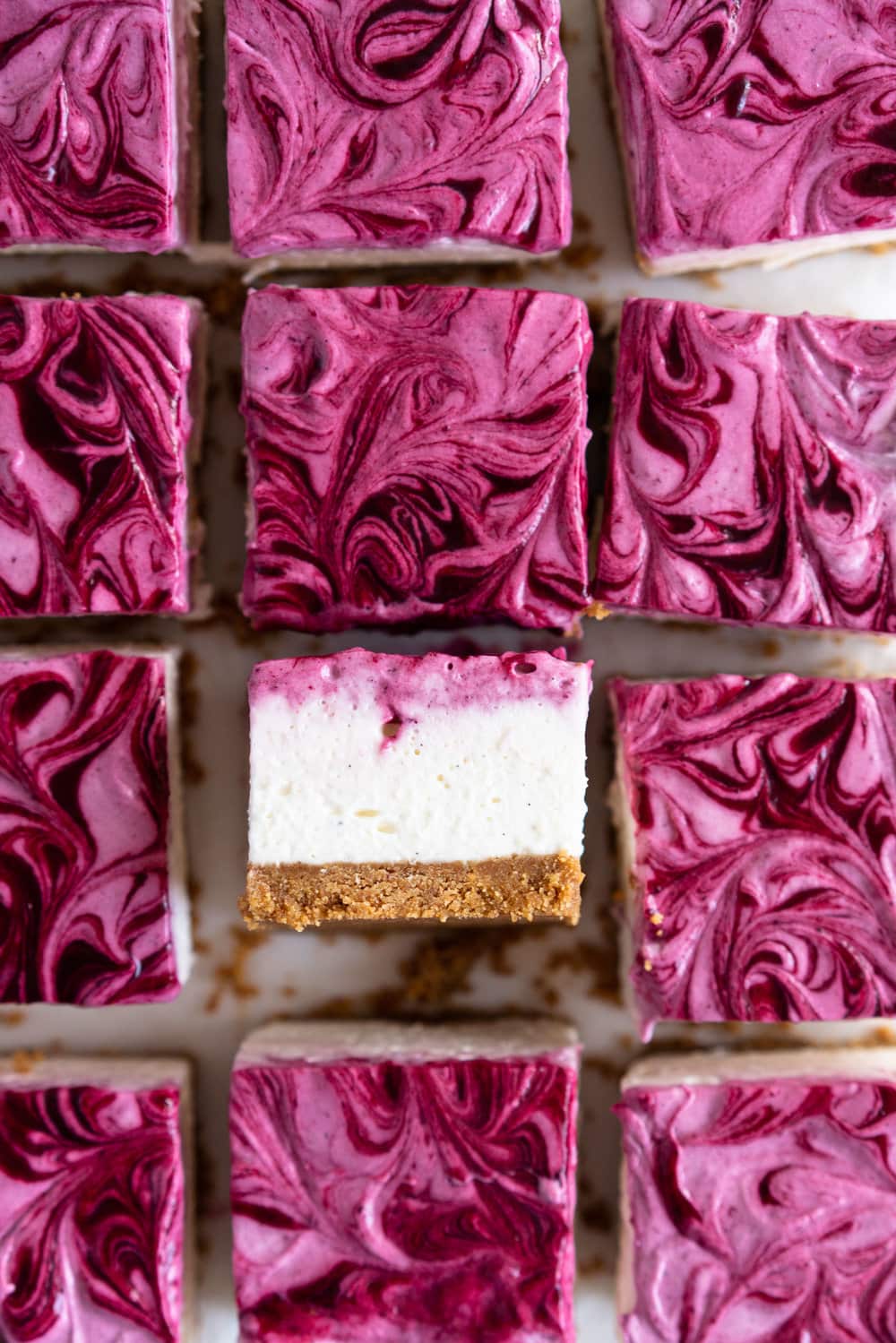 No Bake Mixed Berry Cheesecake Bars - delicious graham cracker crust, topped with a silky vanilla bean no bake filling, and finished with a beautiful marbled swirl of mixed berry coulis. perfect No bake, low effort dessert for any time of the year. #nobake #cheesecake #cheesecakebars #mixedberry #coulis