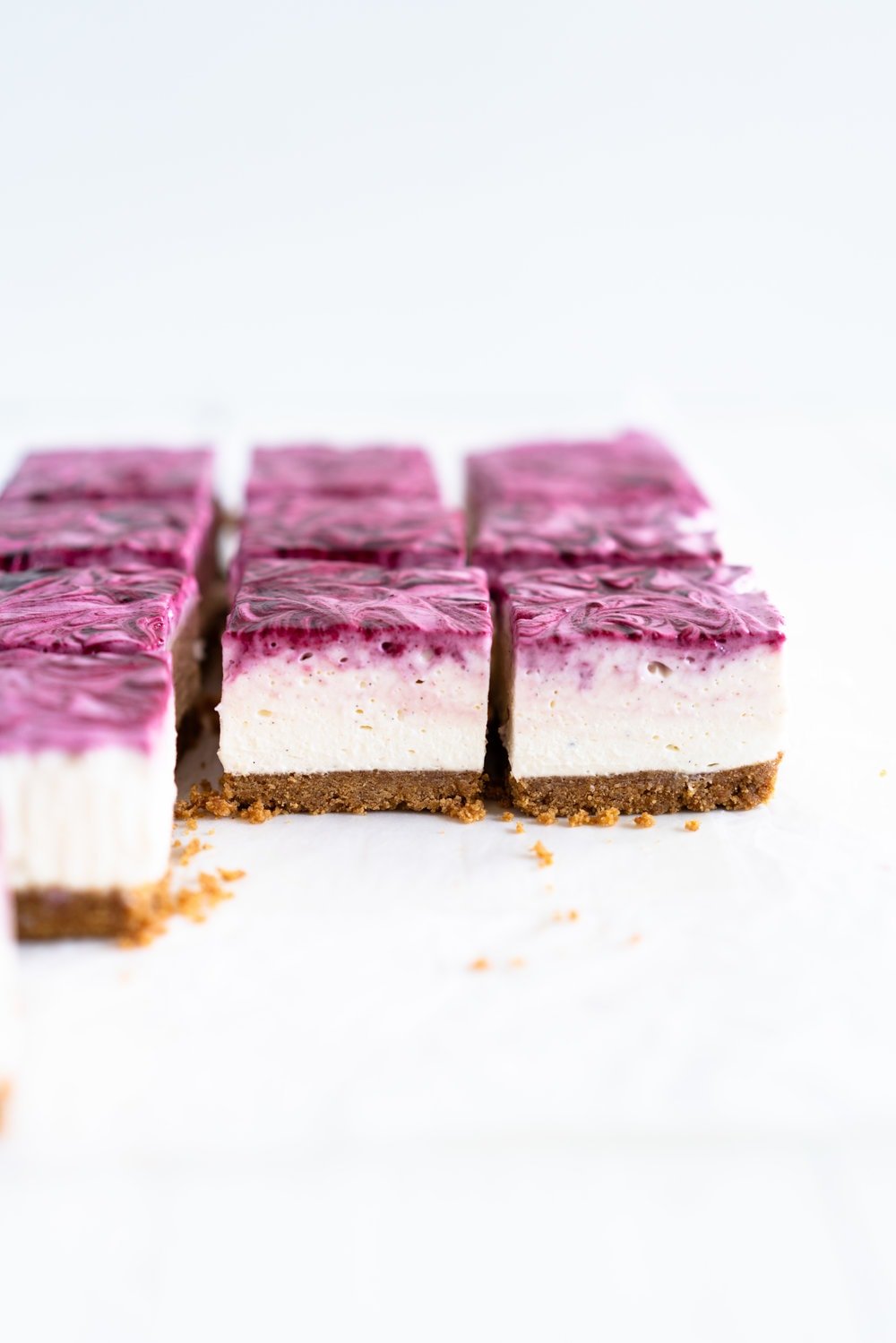 No Bake Mixed Berry Cheesecake Bars - delicious graham cracker crust, topped with a silky vanilla bean no bake filling, and finished with a beautiful marbled swirl of mixed berry coulis. perfect No bake, low effort dessert for any time of the year. #nobake #cheesecake #cheesecakebars #mixedberry #coulis