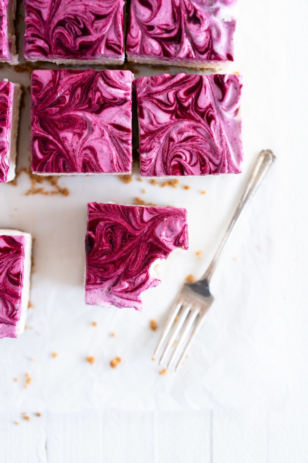 No Bake Mixed Berry Cheesecake Bars - delicious graham cracker crust, topped with a silky vanilla bean no bake filling, and finished with a beautiful marbled swirl of mixed berry coulis. perfect No bake, low effort dessert for any time of the year. #nobake #cheesecake #cheesecakebars #mixedberry #coulis