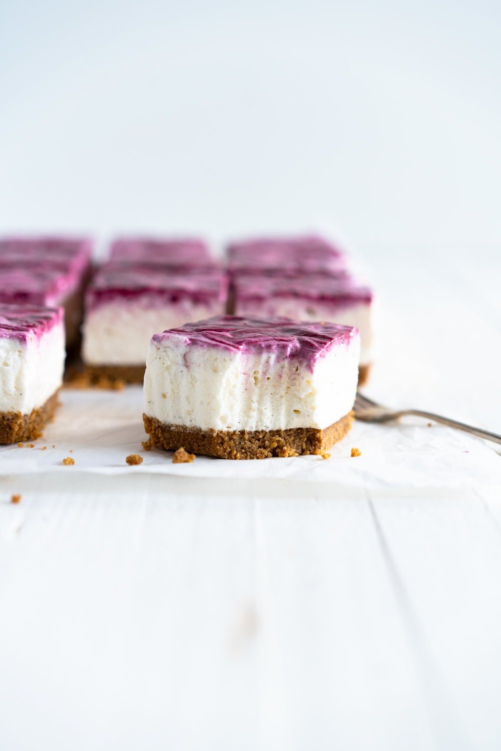 No Bake Mixed Berry Cheesecake Bars - delicious graham cracker crust, topped with a silky vanilla bean no bake filling, and finished with a beautiful marbled swirl of mixed berry coulis. perfect No bake, low effort dessert for any time of the year. #nobake #cheesecake #cheesecakebars #mixedberry #coulis
