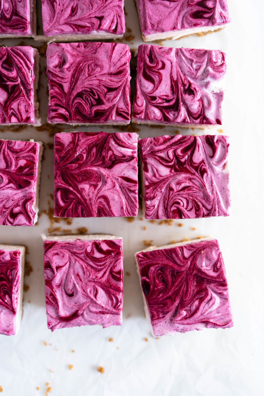 No Bake Mixed Berry Cheesecake Bars - delicious graham cracker crust, topped with a silky vanilla bean no bake filling, and finished with a beautiful marbled swirl of mixed berry coulis. perfect No bake, low effort dessert for any time of the year. #nobake #cheesecake #cheesecakebars #mixedberry #coulis