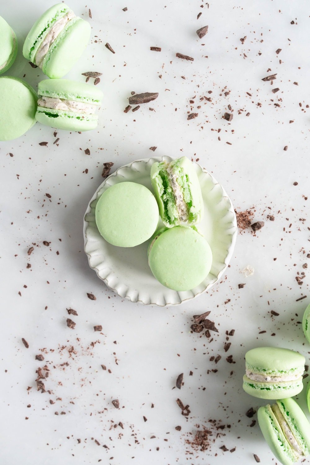 Mint Chocolate Chip Macarons with German buttercream. Delicate French macaron shells are sandwiched together by a mint chocolate chip german buttercream that tastes just like ice cream! #mintchocolatechip #mintchip #frenchmacarons #macarons #recipe #howtomake