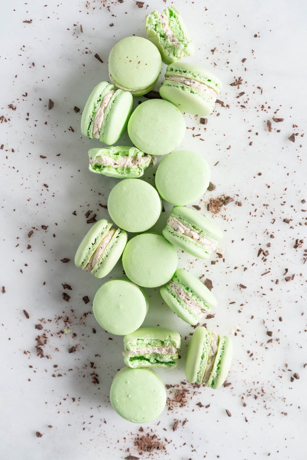 Mint Chocolate Chip Macarons with German buttercream. Delicate French macaron shells are sandwiched together by a mint chocolate chip german buttercream that tastes just like ice cream! #mintchocolatechip #mintchip #frenchmacarons #macarons #recipe #howtomake