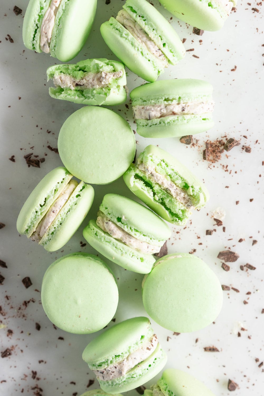 Mint Chocolate Chip Macarons with German buttercream. Delicate French macaron shells are sandwiched together by a mint chocolate chip german buttercream that tastes just like ice cream! #mintchocolatechip #mintchip #frenchmacarons #macarons #recipe #howtomake