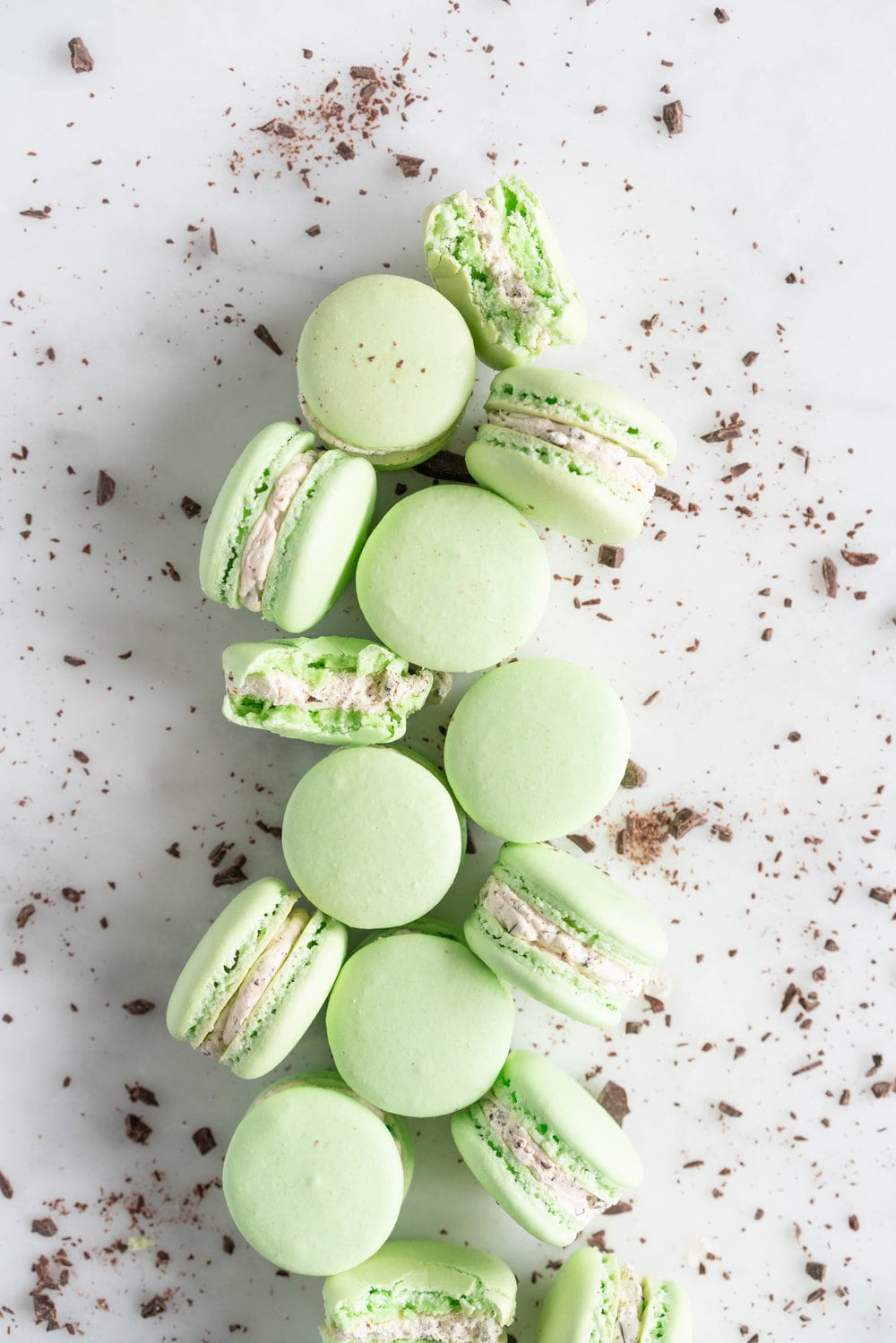 Mint Chocolate Chip Macarons with German buttercream. Delicate French macaron shells are sandwiched together by a mint chocolate chip german buttercream that tastes just like ice cream! #mintchocolatechip #mintchip #frenchmacarons #macarons #recipe #howtomake
