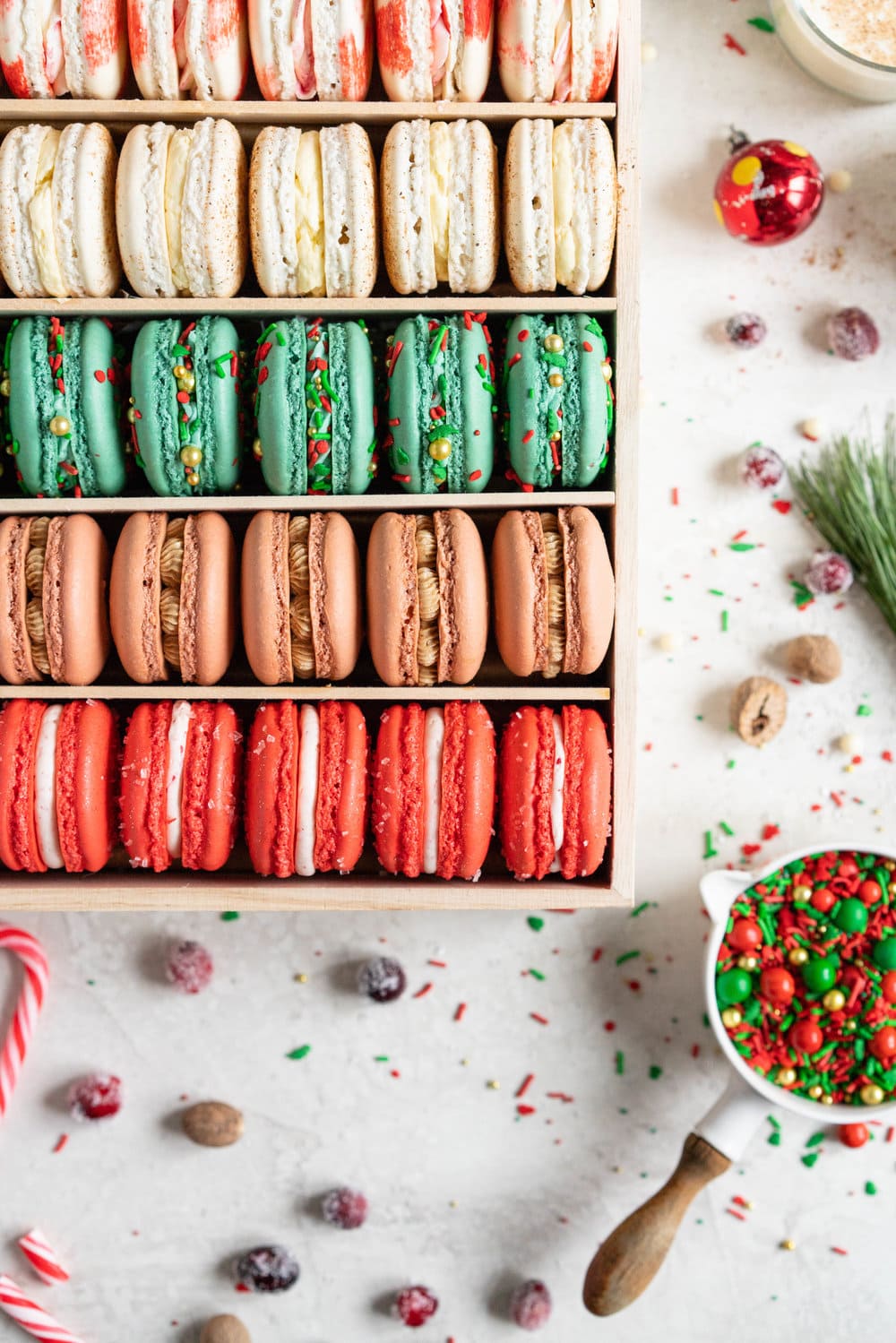 The Ultimate Christmas Macaron box - a cute, gluten free twist on the traditional cookie box. This cookie box is filled with the flavours of christmas - Candy Cane, Eggnog, Christmasfetti, Gingerbread, and cranberry. Each macaron is filled with a delicious complementary filling - ranging from american buttercream to German buttercream. This macaron box would make the perfect homemade gift. Grab the recipes now!