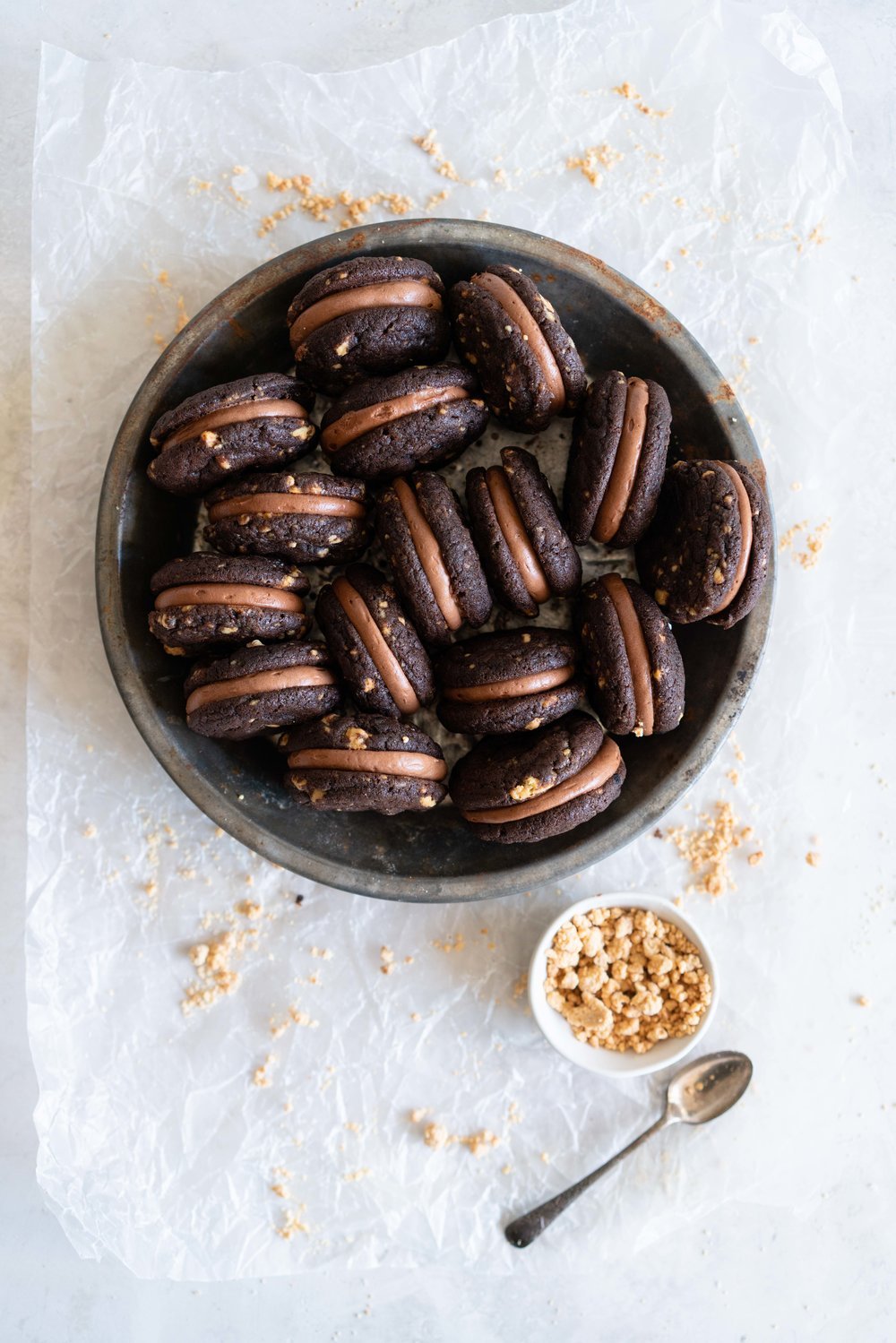 Caramelised White Chocolate Brownie Cookies with Salted Dark Chocolate German Buttercream. Perfect tiny mouthfuls of soft chocolate brownie cookie filled with caramelised white chocolate specks, and sandwiched with silky buttercream. These are bound to become your new favourite. #sandwichcookies #browniecookie #germanbuttercream