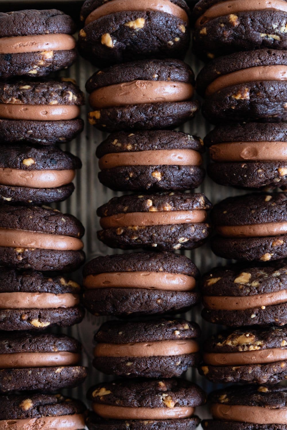 Caramelised White Chocolate Brownie Cookies with Salted Dark Chocolate German Buttercream. Perfect tiny mouthfuls of soft chocolate brownie cookie filled with caramelised white chocolate specks, and sandwiched with silky buttercream. These are bound to become your new favourite. #sandwichcookies #browniecookie #germanbuttercream