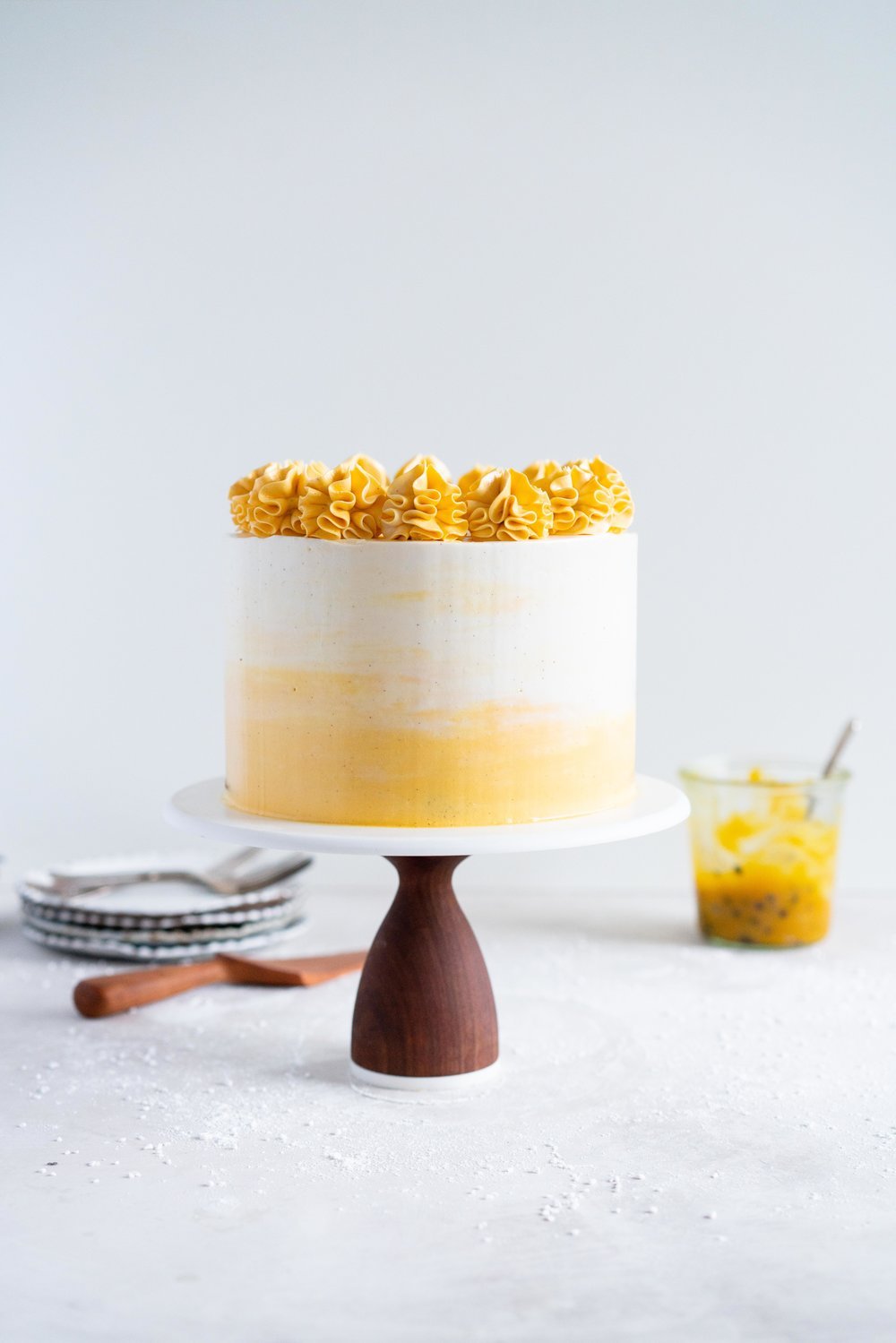 Vanilla Layer Cake with Passionfruit Curd and Vanilla Swiss Meringue Buttercream. Perfect for any occasion - layers of vanilla cake are sandwiched with a silky vanilla bean swiss meringue buttercream, and filled with a tangy, creamy passionfruit curd. #layercake #passionfruitcake