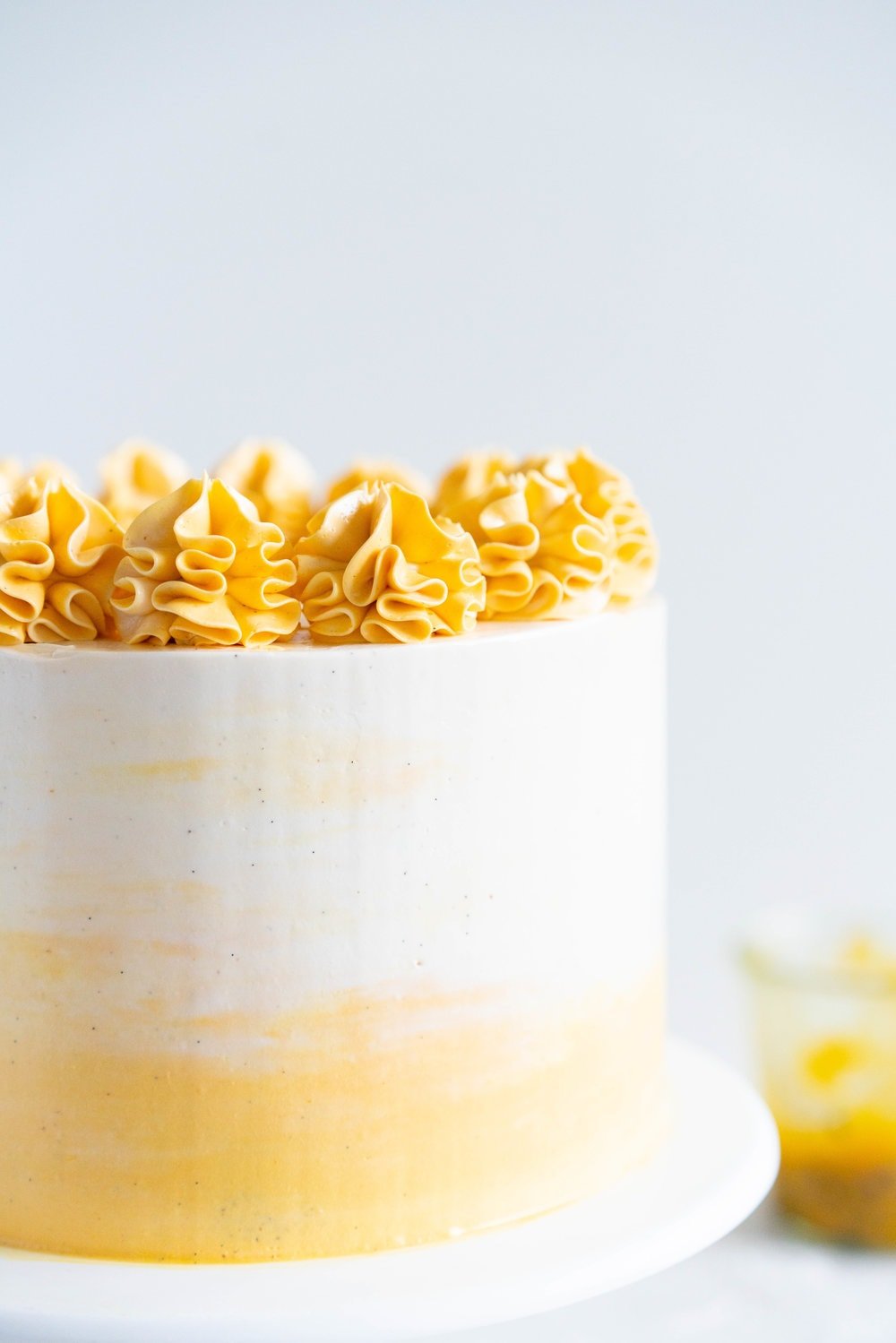Vanilla Layer Cake with Passionfruit Curd and Vanilla Swiss Meringue Buttercream. Perfect for any occasion - layers of vanilla cake are sandwiched with a silky vanilla bean swiss meringue buttercream, and filled with a tangy, creamy passionfruit curd. #layercake #passionfruitcake