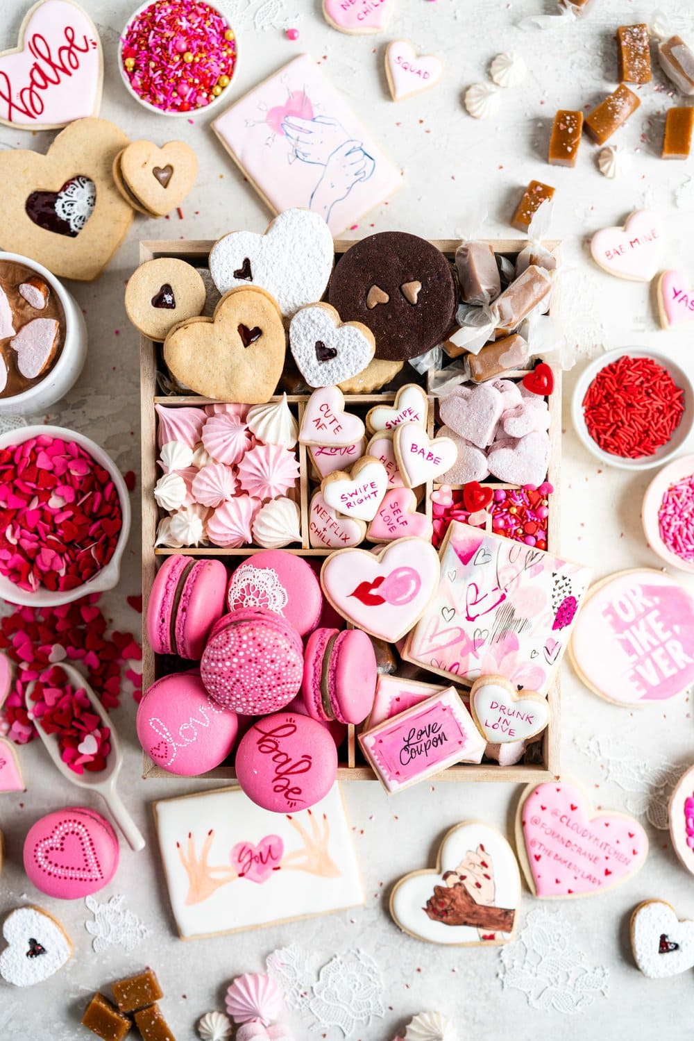The Ultimate Valentine's Day treat box - a perfect mix of cookies and sweet treats to help celebrate valentine's day or the ones you love. This would make the most amazing gift - we included macarons, painted sugar cookies, linzer cookies, chocolate sandwich cookies, meringue kisses, soft earl grey caramels, and marshmallow hearts. #valentinesday #cookiebox