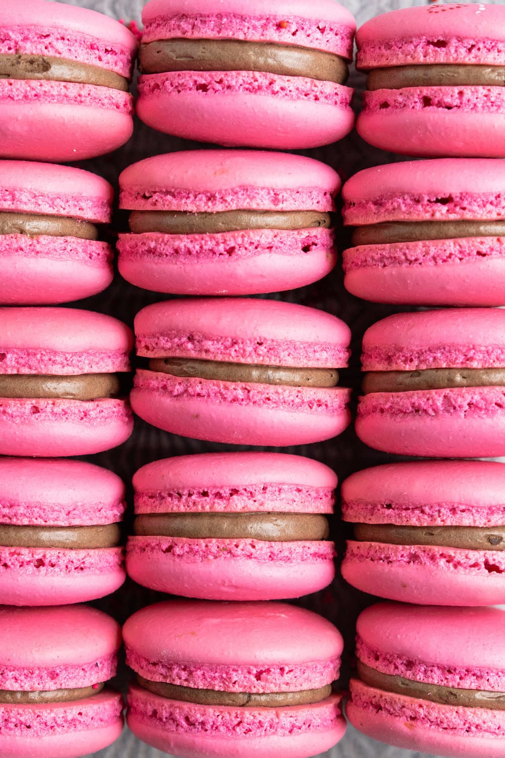 Raspberry and Dark Chocolate Macarons - A classic pink shell, filled with a homemade raspberry quick jam, and a silky Dark chocolate swiss meringue buttercream, deepened with a little black cocoa. These are a classic valentine's day pairing, and would be perfect as a gift, but would also make an amazing anytime treat for a chocolate or berry lover. #frenchmacaron #valentinesmacaron