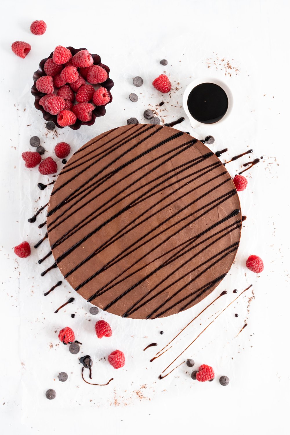 No Bake Chocolate Cheesecake - a chocolate graham cracker base is topped with a silky, no bake chocolate cheesecake filling, and finished with a drizzle of sweet, sticky raspberry balsamic glaze. This dessert comes together quickly, and is perfect for feeding a crowd. #cheesecake #chocolatecheesecake #nobakecheesecake