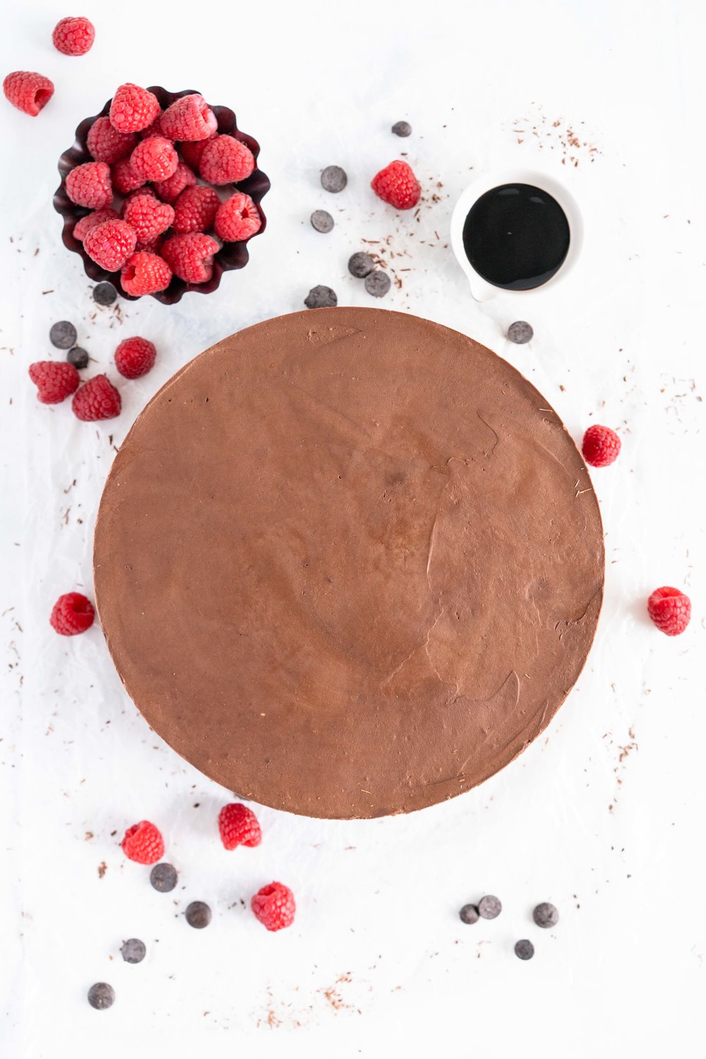 No Bake Chocolate Cheesecake - a chocolate graham cracker base is topped with a silky, no bake chocolate cheesecake filling, and finished with a drizzle of sweet, sticky raspberry balsamic glaze. This dessert comes together quickly, and is perfect for feeding a crowd. #cheesecake #chocolatecheesecake #nobakecheesecake