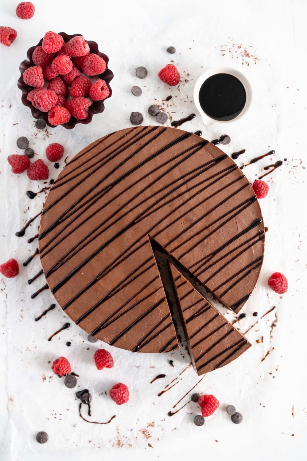 No Bake Chocolate Cheesecake - a chocolate graham cracker base is topped with a silky, no bake chocolate cheesecake filling, and finished with a drizzle of sweet, sticky raspberry balsamic glaze. This dessert comes together quickly, and is perfect for feeding a crowd. #cheesecake #chocolatecheesecake #nobakecheesecake