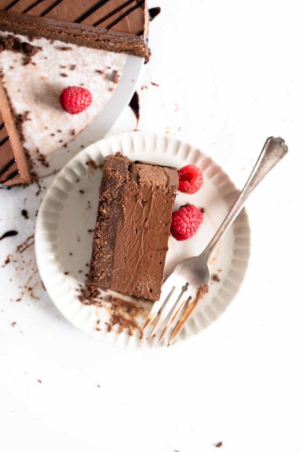 No Bake Chocolate Cheesecake - a chocolate graham cracker base is topped with a silky, no bake chocolate cheesecake filling, and finished with a drizzle of sweet, sticky raspberry balsamic glaze. This dessert comes together quickly, and is perfect for feeding a crowd. #cheesecake #chocolatecheesecake #nobakecheesecake