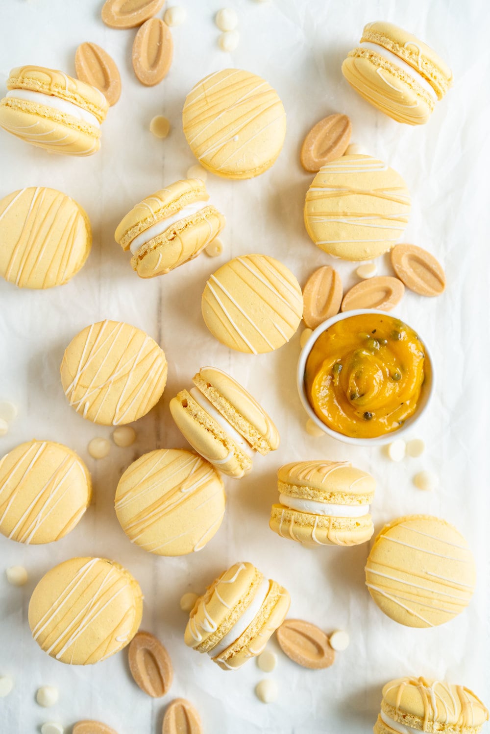 Passionfruit and White Chocolate Macarons - Vanilla bean macaron shell, filled with white chocolate swiss meringue buttercream and tangy passionfruit curd, then finished with a chocolate drizzle. #frenchmacaron #macarons #passionfruit