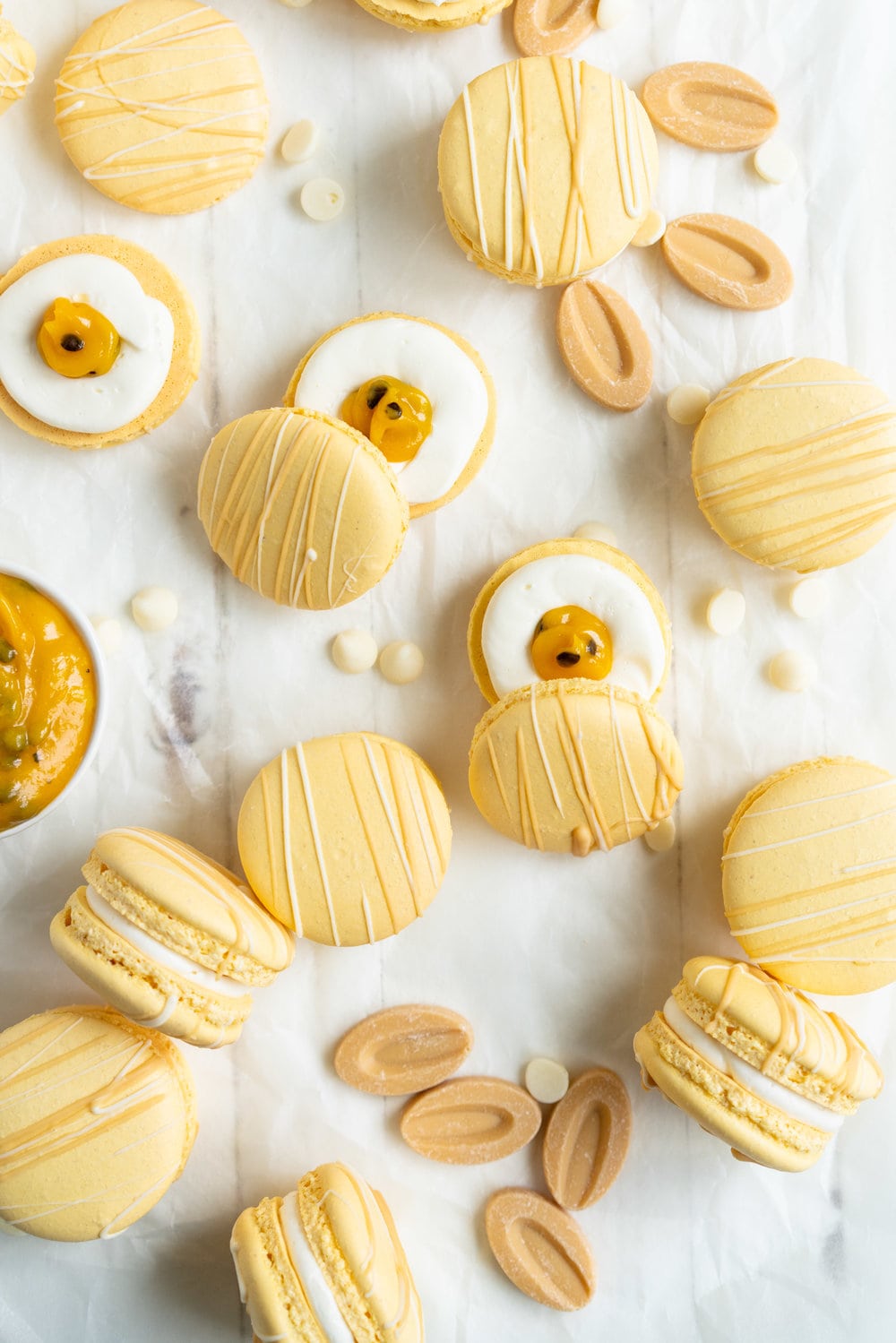 Passionfruit and White Chocolate Macarons - Vanilla bean macaron shell, filled with white chocolate swiss meringue buttercream and tangy passionfruit curd, then finished with a chocolate drizzle. #frenchmacaron #macarons #passionfruit
