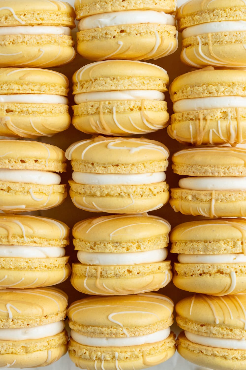 Passionfruit and White Chocolate Macarons - Vanilla bean macaron shell, filled with white chocolate swiss meringue buttercream and tangy passionfruit curd, then finished with a chocolate drizzle. #frenchmacaron #macarons #passionfruit