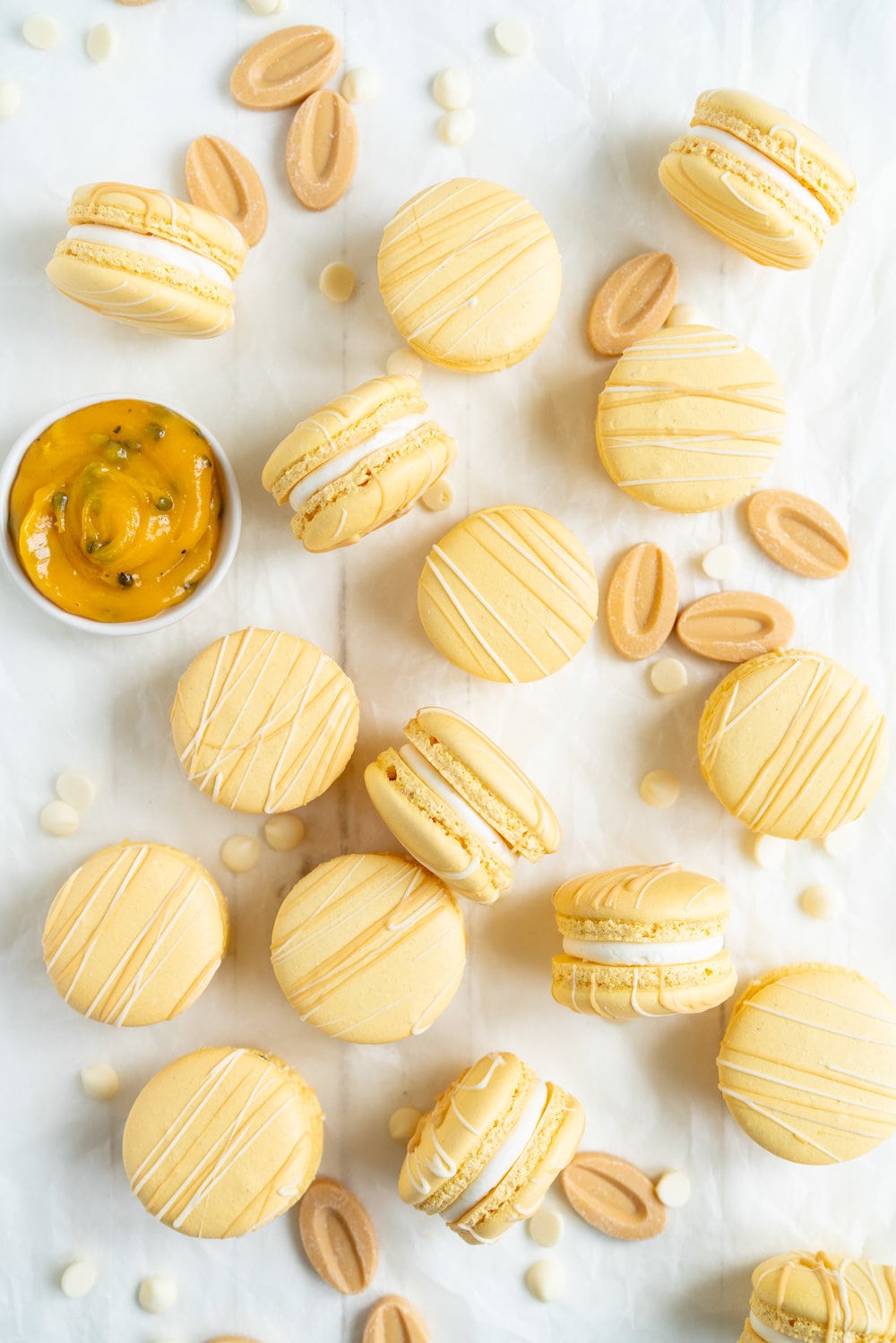 Passionfruit and White Chocolate Macarons - Vanilla bean macaron shell, filled with white chocolate swiss meringue buttercream and tangy passionfruit curd, then finished with a chocolate drizzle. #frenchmacaron #macarons #passionfruit