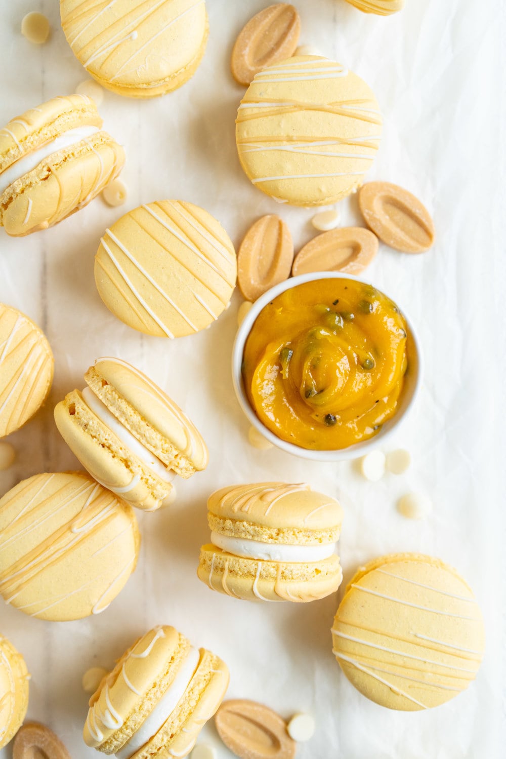 Passionfruit and White Chocolate Macarons - Vanilla bean macaron shell, filled with white chocolate swiss meringue buttercream and tangy passionfruit curd, then finished with a chocolate drizzle. #frenchmacaron #macarons #passionfruit