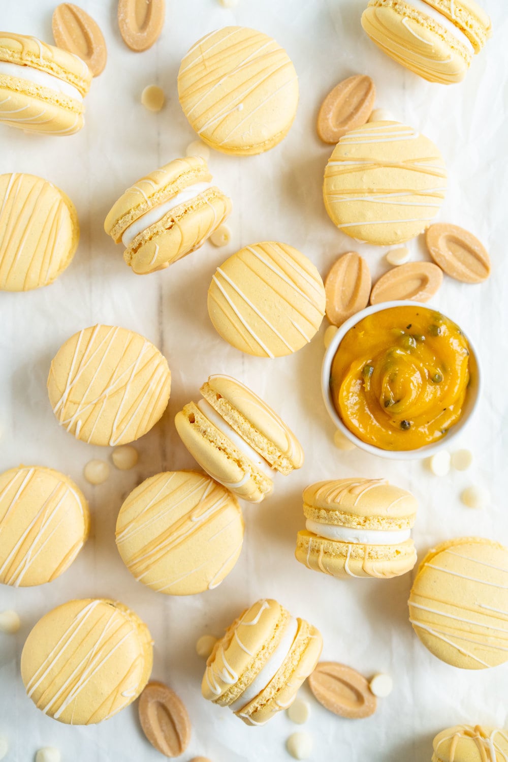 Passionfruit and White Chocolate Macarons - Vanilla bean macaron shell, filled with white chocolate swiss meringue buttercream and tangy passionfruit curd, then finished with a chocolate drizzle. #frenchmacaron #macarons #passionfruit
