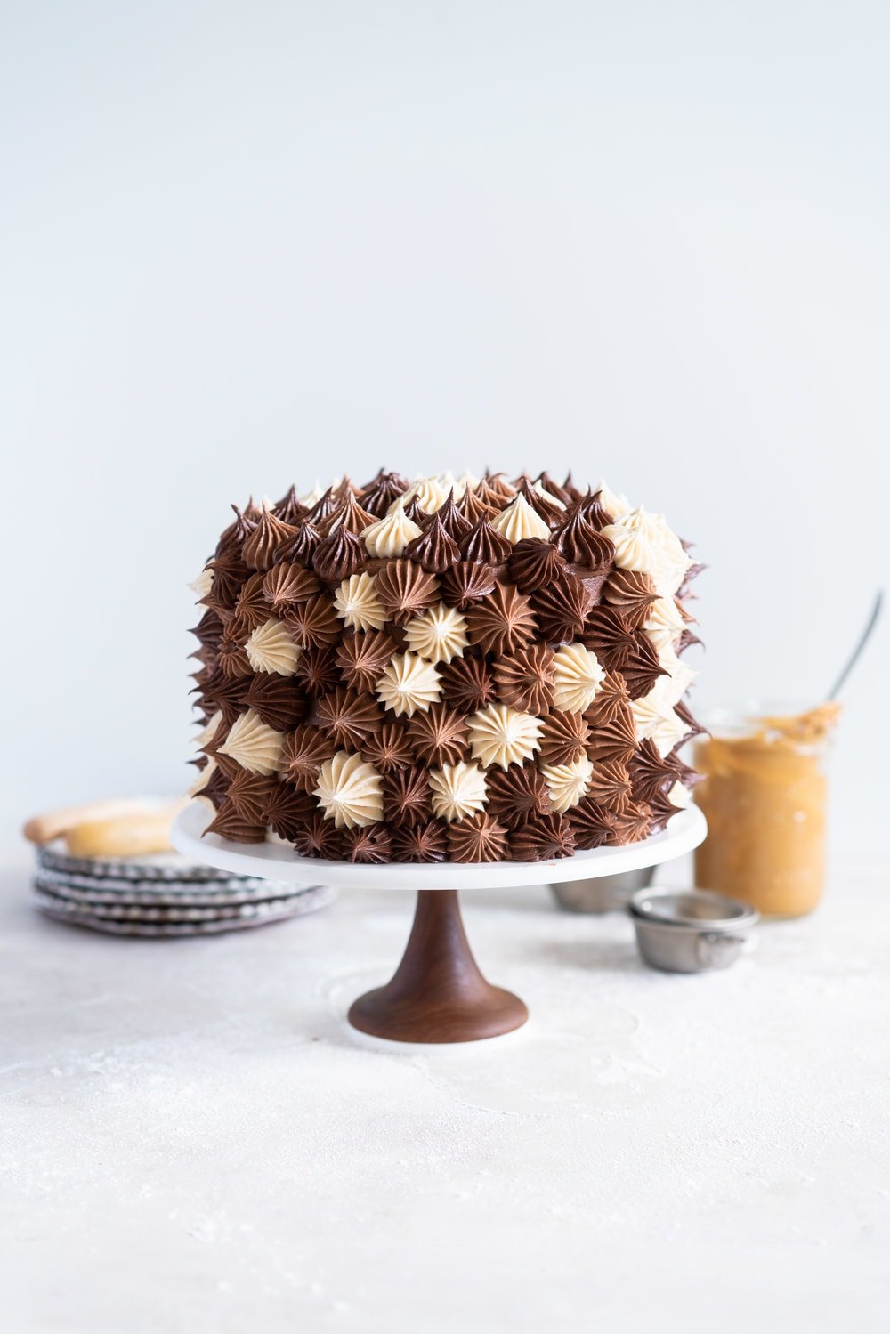 Chocolate and Peanut Butter Layer Cake with Chocolate and Peanut Butter Buttercream - this party cake is from the latest book from Bake from Scratch Magazine. Soft chocolate and peanut butter cake layers are sandwiched with chocolate and peanut butter buttercream, then finished off with playful blobs of the buttercream to create the perfect chocolate ombre cake. This cake is easy to make and is great to serve a crowd - you can't go wrong with peanut butter and chocolate! #chocolatecake #peanutbuttercake #chocolatebuttercream #peanutbutterbuttercream