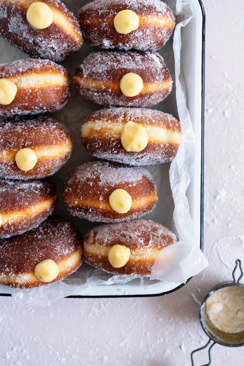 Malasadas with Liliko'i (Passionfruit) Pastry Cream Filling from Alana Kysar's new book, Aloha Kitchen. Malasadas are Portuguese style doughnuts, which are soft and fluffy. They are fried off, then rolled in sugar, then filled with a silky liliko'i pastry cream. These are the perfect indulgent treat, and are super easy to make. #malasadas #doughnuts #lilikoi #passionfruit