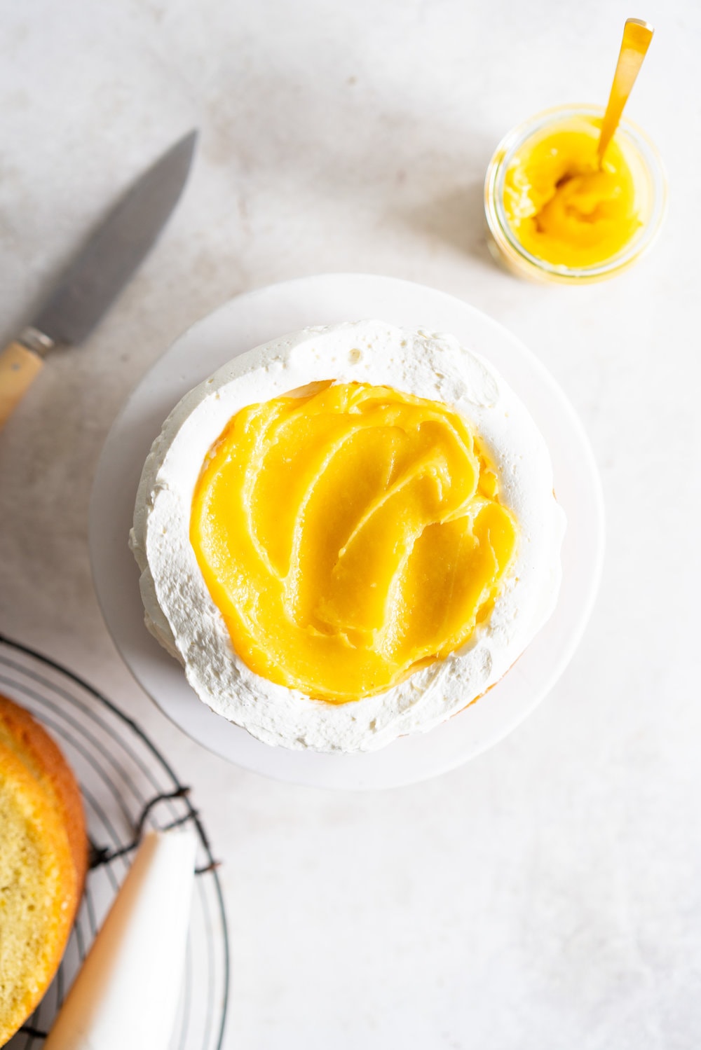 Olive Oil Layer Cake with Meyer Lemon Curd and Rosemary German Buttercream. Fruity olive oil cake is filled with a zesty meyer lemon curd, and finished in a semi naked style with a rosemary german buttercream and spring flowers. #nakedcake #oliveoilcake #meyerlemon