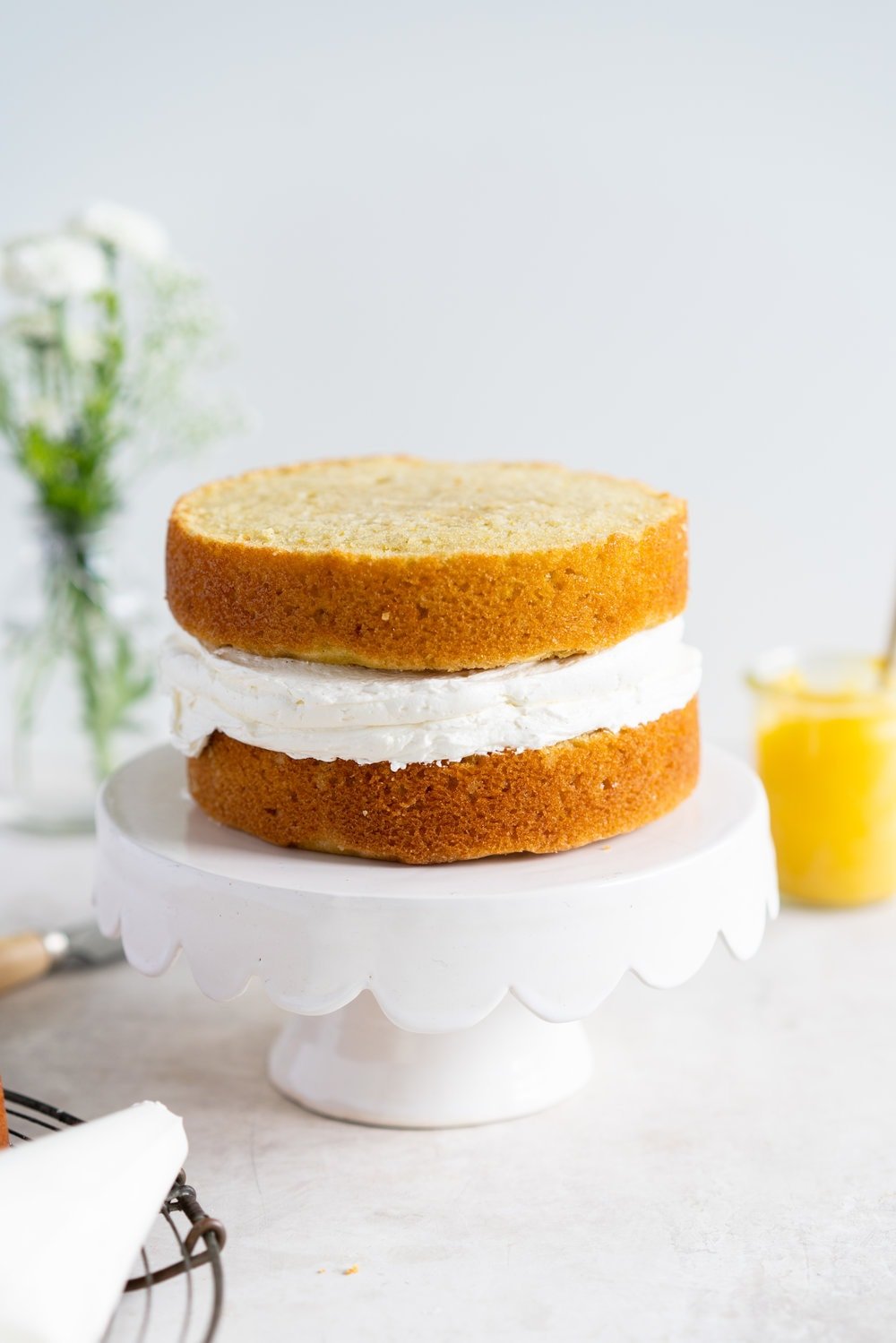 Olive Oil Layer Cake with Meyer Lemon Curd and Rosemary German Buttercream. Fruity olive oil cake is filled with a zesty meyer lemon curd, and finished in a semi naked style with a rosemary german buttercream and spring flowers. #nakedcake #oliveoilcake #meyerlemon
