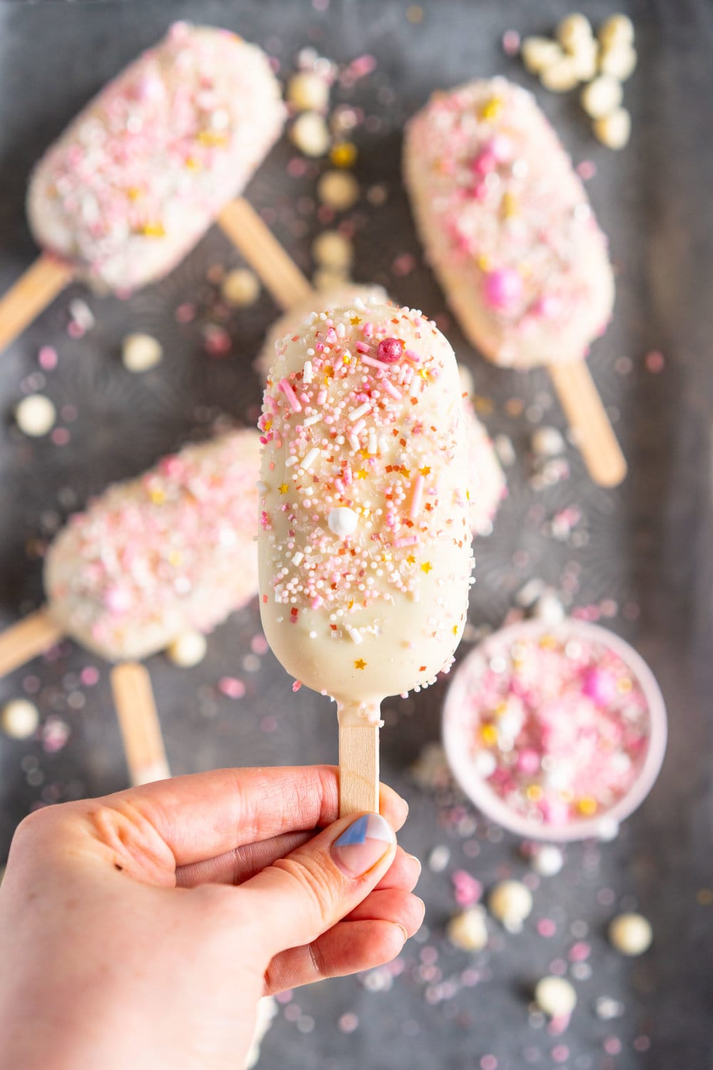 A simple stir together raspberry philadelphia style ice-cream base is churned then elevated with a raspberry ripple, before being frozen into ice cream pops and finished with a super easy white chocolate magic shell and loads of sprinkles. The perfect fancy treat for summer just around the corner - these last for a long time in the freezer so are great to have on hand when the ice cream craving strikes! #icecreampop #raspberryicecream #raspberrywhitechocolate