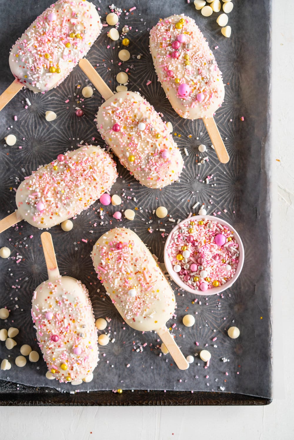 A simple stir together raspberry philadelphia style ice-cream base is churned then elevated with a raspberry ripple, before being frozen into ice cream pops and finished with a super easy white chocolate magic shell and loads of sprinkles. The perfect fancy treat for summer just around the corner - these last for a long time in the freezer so are great to have on hand when the ice cream craving strikes! #icecreampop #raspberryicecream #raspberrywhitechocolate