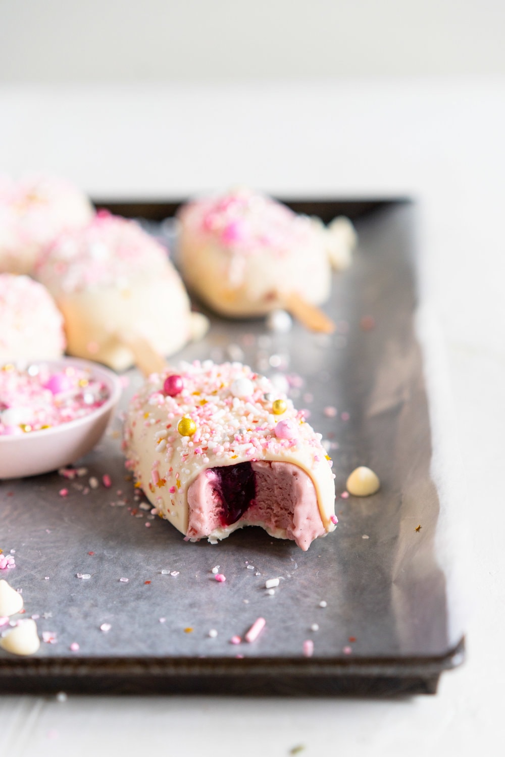 A simple stir together raspberry philadelphia style ice-cream base is churned then elevated with a raspberry ripple, before being frozen into ice cream pops and finished with a super easy white chocolate magic shell and loads of sprinkles. The perfect fancy treat for summer just around the corner - these last for a long time in the freezer so are great to have on hand when the ice cream craving strikes! #icecreampop #raspberryicecream #raspberrywhitechocolate